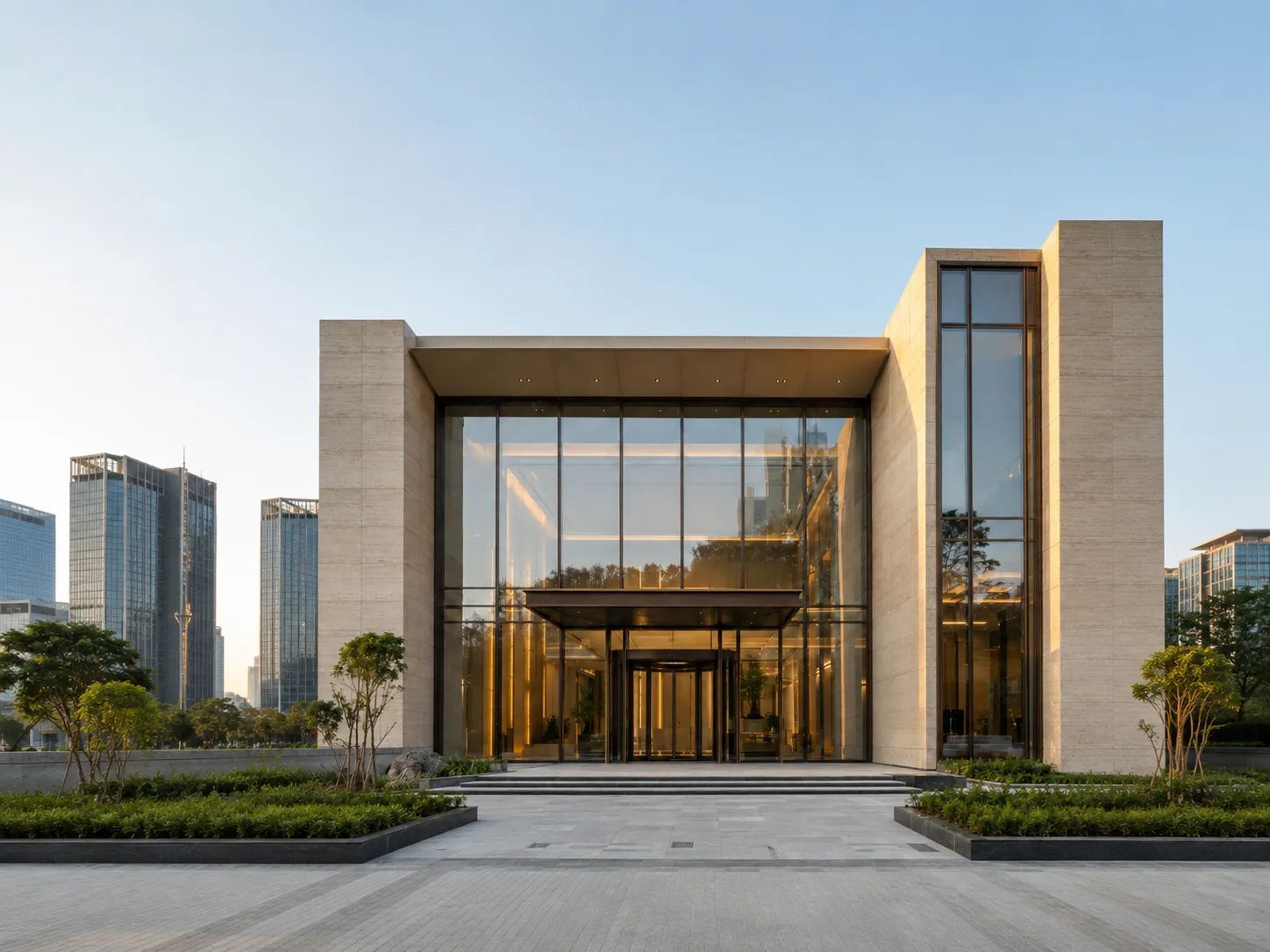 Entrance of a modern travertine and glass office building in soft morning light.